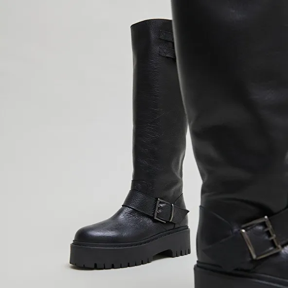 Boots with straps and notched soles in black grained leather